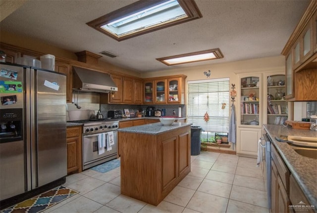 2517 E Mile 4th Rd, Mission, TX 78573 - kitchen with appliances with stainless steel finishes, wall chimney exhaust hood, a textured ceiling, brown cabinets, and glass insert cabinets