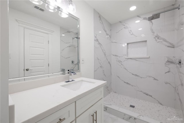 bathroom featuring tiled shower and vanity