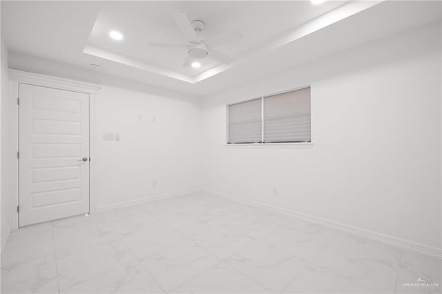 empty room featuring a raised ceiling and ceiling fan