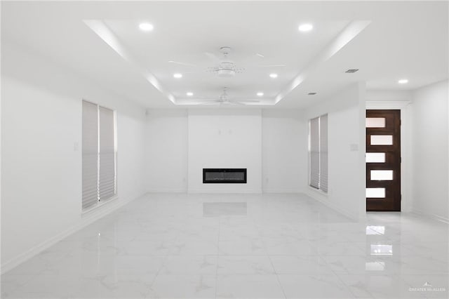 unfurnished living room with a raised ceiling and ceiling fan