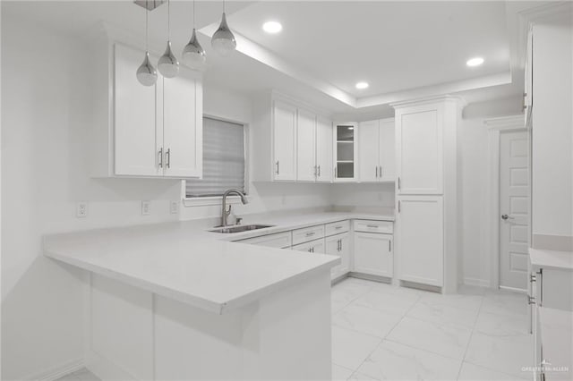 kitchen with kitchen peninsula, white cabinetry, sink, and pendant lighting