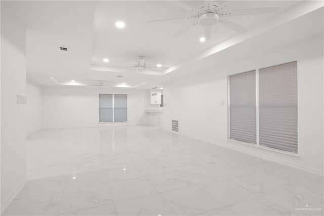 unfurnished room featuring a raised ceiling and ceiling fan