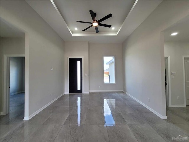 unfurnished room featuring ceiling fan and a raised ceiling