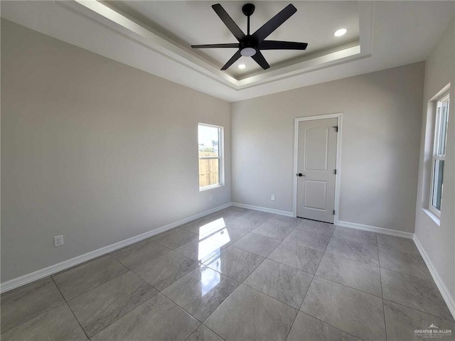 empty room featuring ceiling fan and a tray ceiling