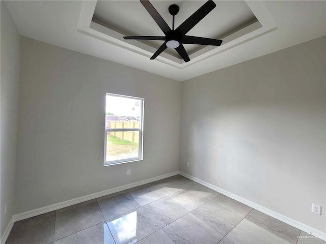 unfurnished room featuring ceiling fan and a raised ceiling