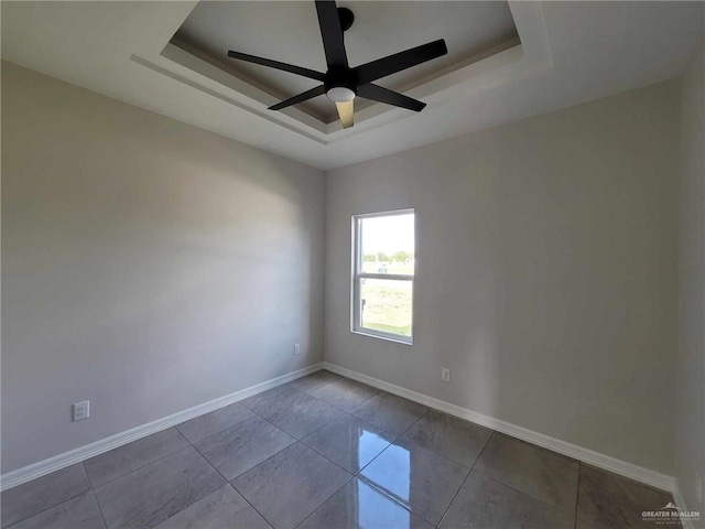 unfurnished room with a tray ceiling, ceiling fan, and light tile patterned flooring