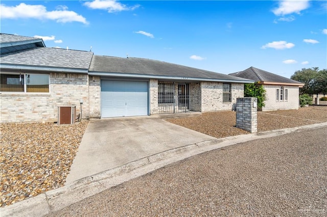1923 Stadler Dr, Mission, TX 78572 - ranch-style house featuring concrete driveway, a garage, brick siding, a shingled roof, and central AC unit