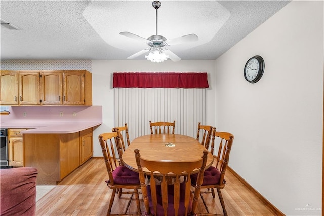 1923 Stadler Dr, Mission, TX 78572 - dining room featuring light wood-style floors, a textured ceiling, a ceiling fan, and baseboards