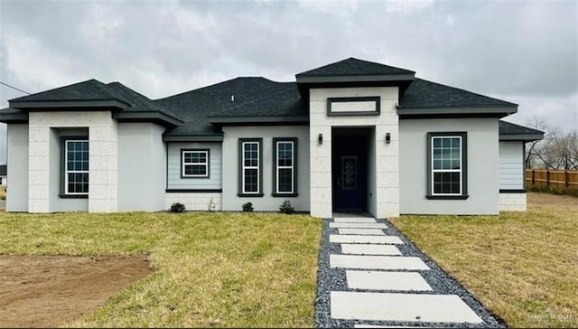 view of front of house featuring a shingled roof, a front yard, and fence