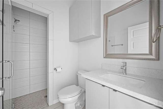 bathroom featuring vanity, a shower with door, and toilet