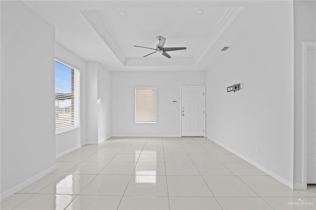 tiled spare room with crown molding, a tray ceiling, and ceiling fan