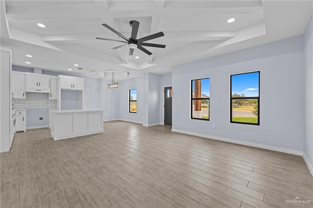 unfurnished living room featuring beamed ceiling, a raised ceiling, and ceiling fan with notable chandelier