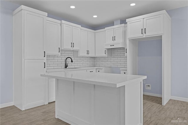 kitchen featuring sink, a center island, white cabinets, and light wood-type flooring