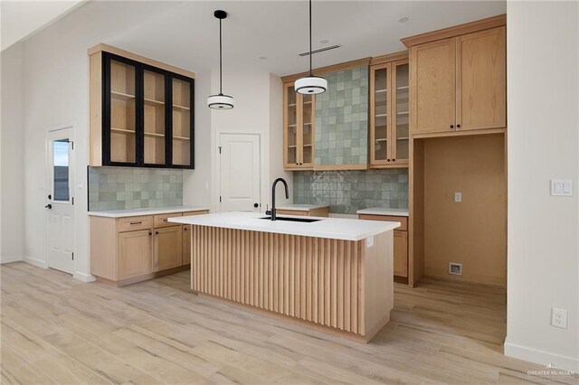 2717 E Versace Dr, Edinburg, TX 78542 - kitchen featuring a sink, backsplash, light wood-style floors, glass insert cabinets, and light countertops