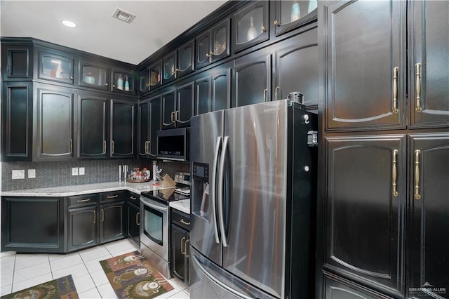 kitchen featuring light tile patterned floors, tasteful backsplash, visible vents, glass insert cabinets, and appliances with stainless steel finishes