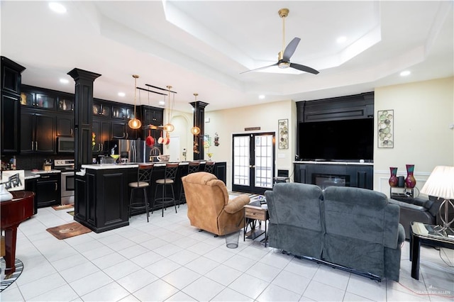 living area featuring ceiling fan, a raised ceiling, and light tile patterned flooring