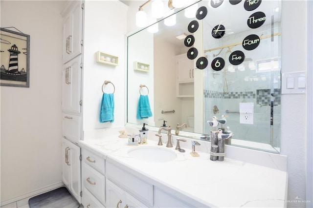 bathroom with tiled shower, vanity, and toilet