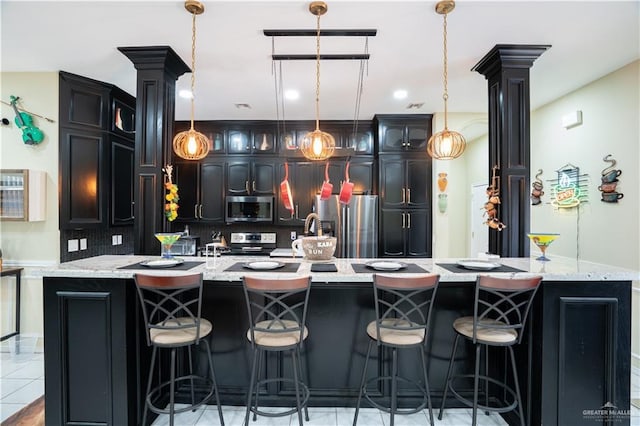 bar with ornate columns, light tile patterned floors, appliances with stainless steel finishes, and pendant lighting