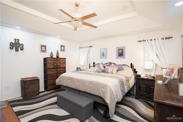 bedroom with recessed lighting, a raised ceiling, a ceiling fan, and baseboards