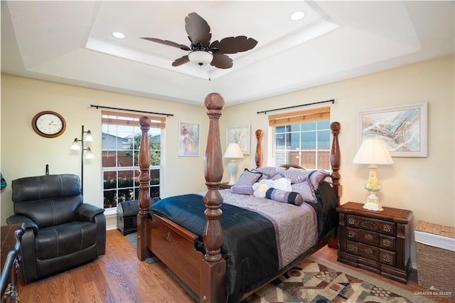 bedroom with light wood-type flooring, a tray ceiling, a ceiling fan, and recessed lighting