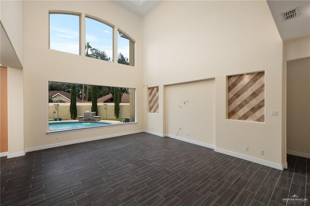 unfurnished living room featuring dark hardwood / wood-style floors and a high ceiling