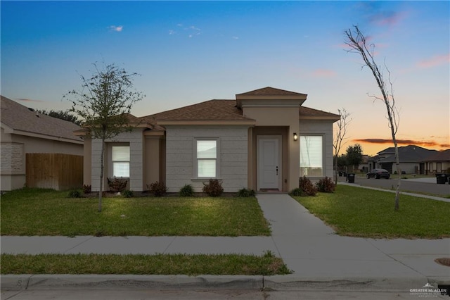 view of front of property with an attached garage, driveway, fence, and a front lawn