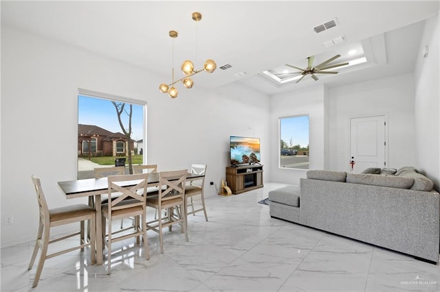 dining area featuring marble finish floor, visible vents, a raised ceiling, and ceiling fan with notable chandelier