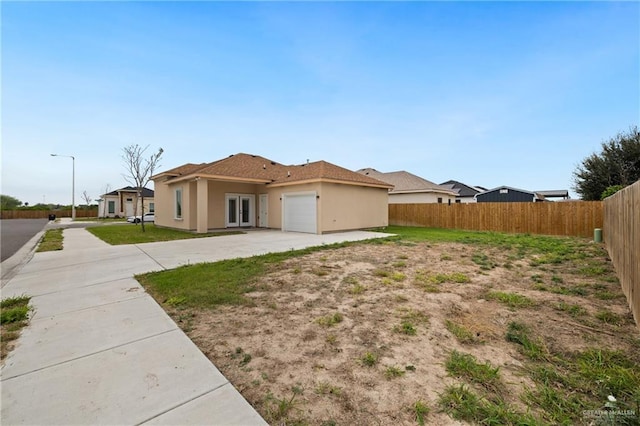 view of front of house with a garage, fence, concrete driveway, and stucco siding