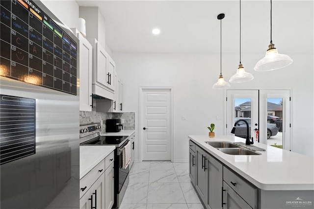 kitchen with a sink, marble finish floor, appliances with stainless steel finishes, light countertops, and backsplash