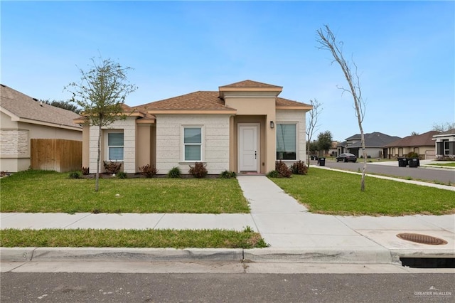 view of front facade with stucco siding, fence, and a front yard