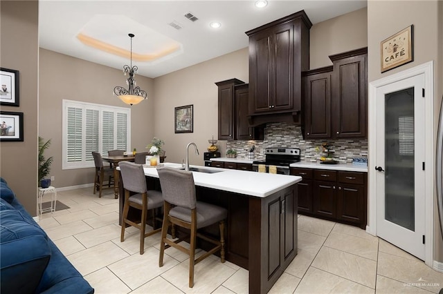 13410 N 36th Ln, Edinburg, TX 78541 - kitchen featuring stainless steel electric range, backsplash, light countertops, a kitchen bar, and decorative light fixtures