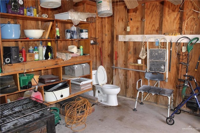 bathroom featuring wood walls, concrete flooring, and toilet