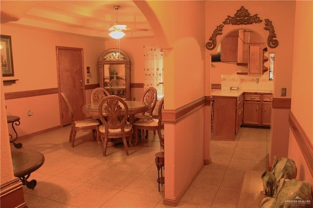 tiled dining space featuring a tray ceiling and ceiling fan