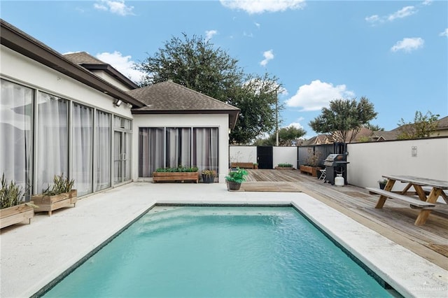 view of swimming pool with grilling area and a deck