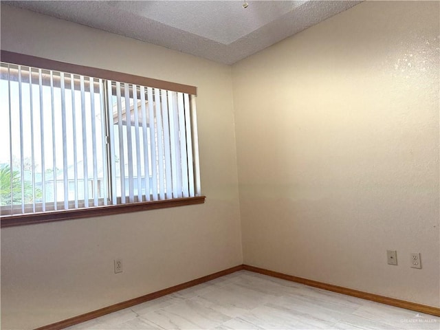 spare room featuring baseboards and a textured ceiling