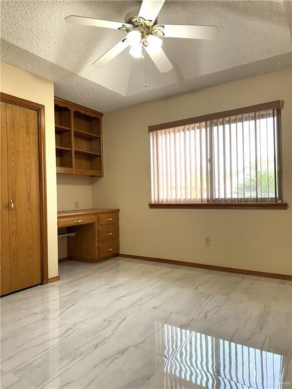 interior space with baseboards, built in study area, ceiling fan, a textured ceiling, and marble finish floor