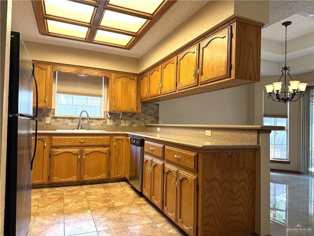 kitchen featuring a peninsula, brown cabinets, appliances with stainless steel finishes, and a sink