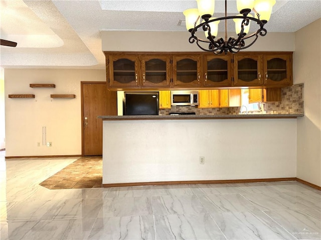 kitchen with stainless steel microwave, backsplash, black refrigerator, brown cabinetry, and marble finish floor