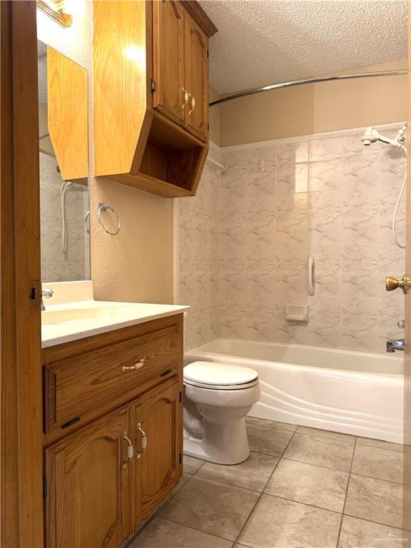 bathroom with toilet, vanity, bathtub / shower combination, tile patterned floors, and a textured ceiling