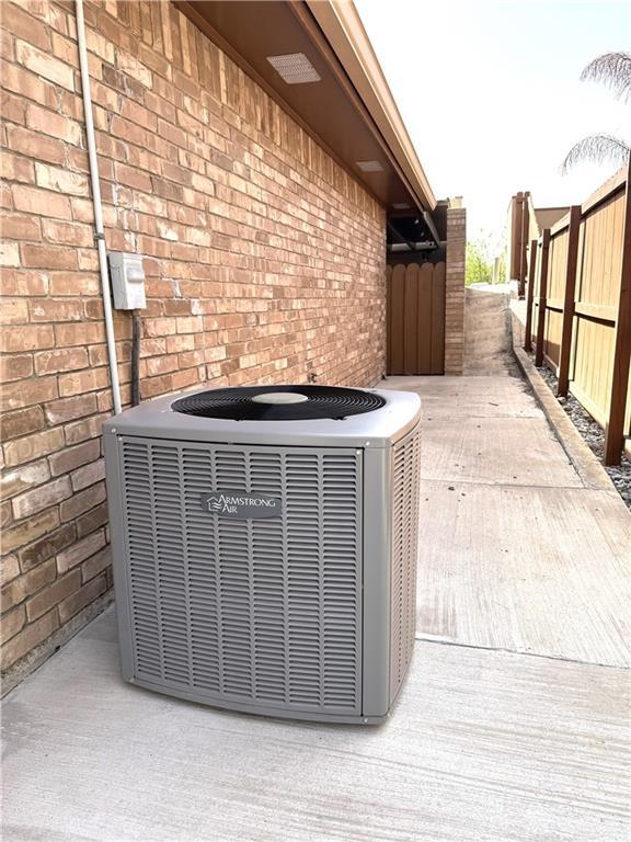 details with fence, central AC unit, and brick siding