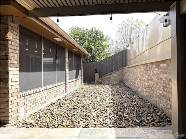 view of home's exterior with a fenced backyard, brick siding, and a sunroom