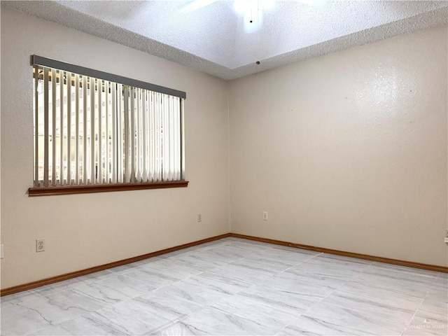 spare room featuring ceiling fan, baseboards, and a textured ceiling