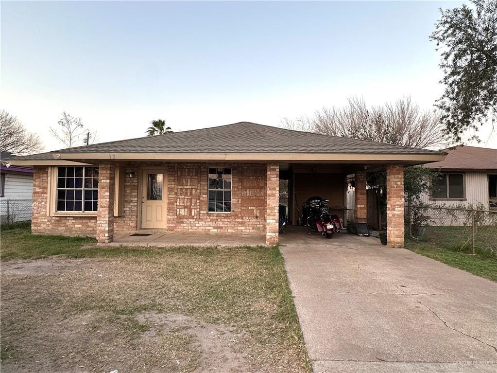 ranch-style house featuring concrete driveway, roof with shingles, and brick siding