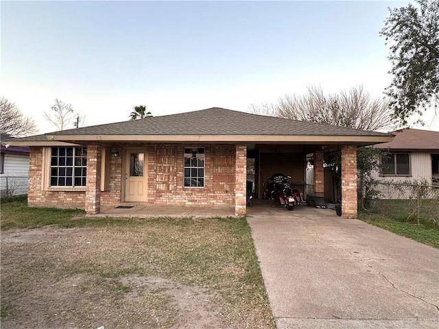 ranch-style house featuring concrete driveway, roof with shingles, and brick siding