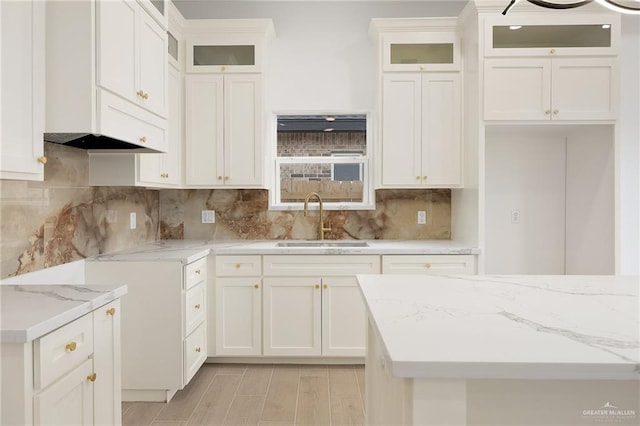 kitchen featuring sink, decorative backsplash, light stone countertops, and white cabinets