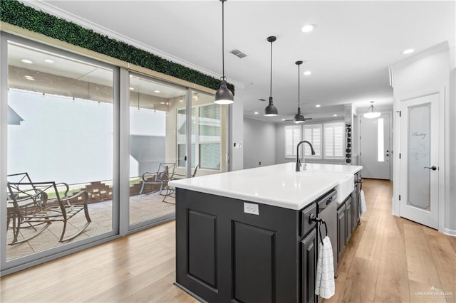 kitchen with light hardwood / wood-style floors, hanging light fixtures, ceiling fan, a center island with sink, and crown molding