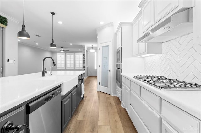 kitchen with appliances with stainless steel finishes, white cabinetry, backsplash, hanging light fixtures, and ceiling fan