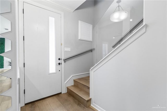 foyer entrance featuring crown molding and light hardwood / wood-style floors