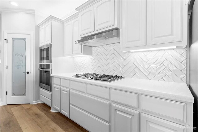 kitchen featuring tasteful backsplash, light hardwood / wood-style floors, ornamental molding, stainless steel appliances, and white cabinets