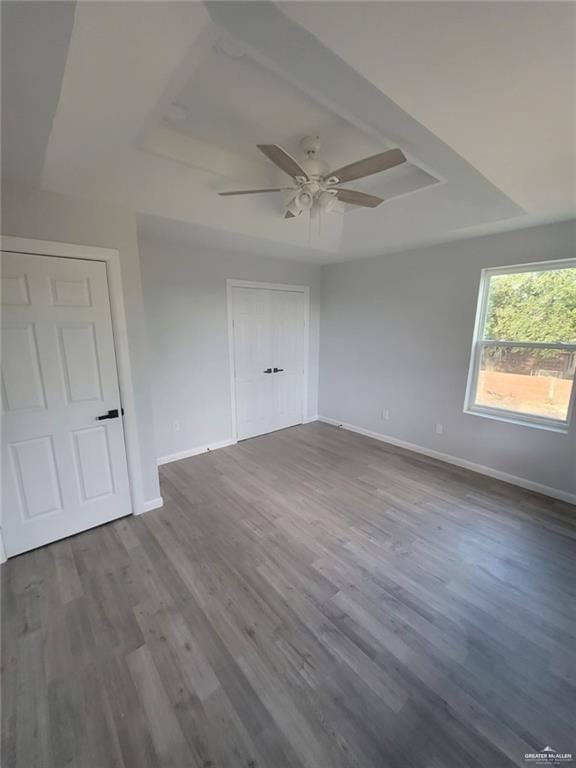 unfurnished room featuring hardwood / wood-style floors, a tray ceiling, and ceiling fan